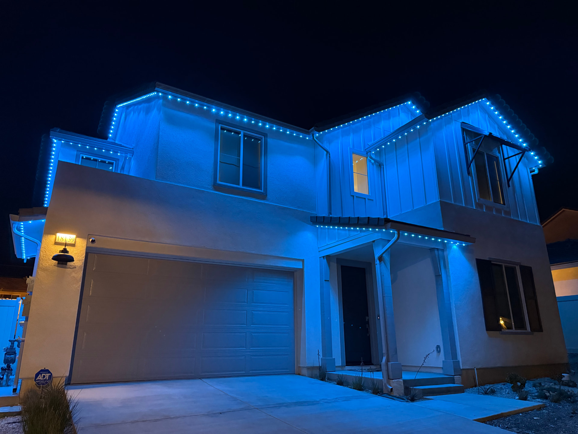 Modern farmhouse outlined in vivid blue permanent LED lighting